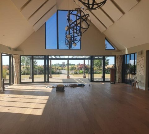 Light-filled vaulted barn hall with garden views, set up for meditation and wellbeing workshops